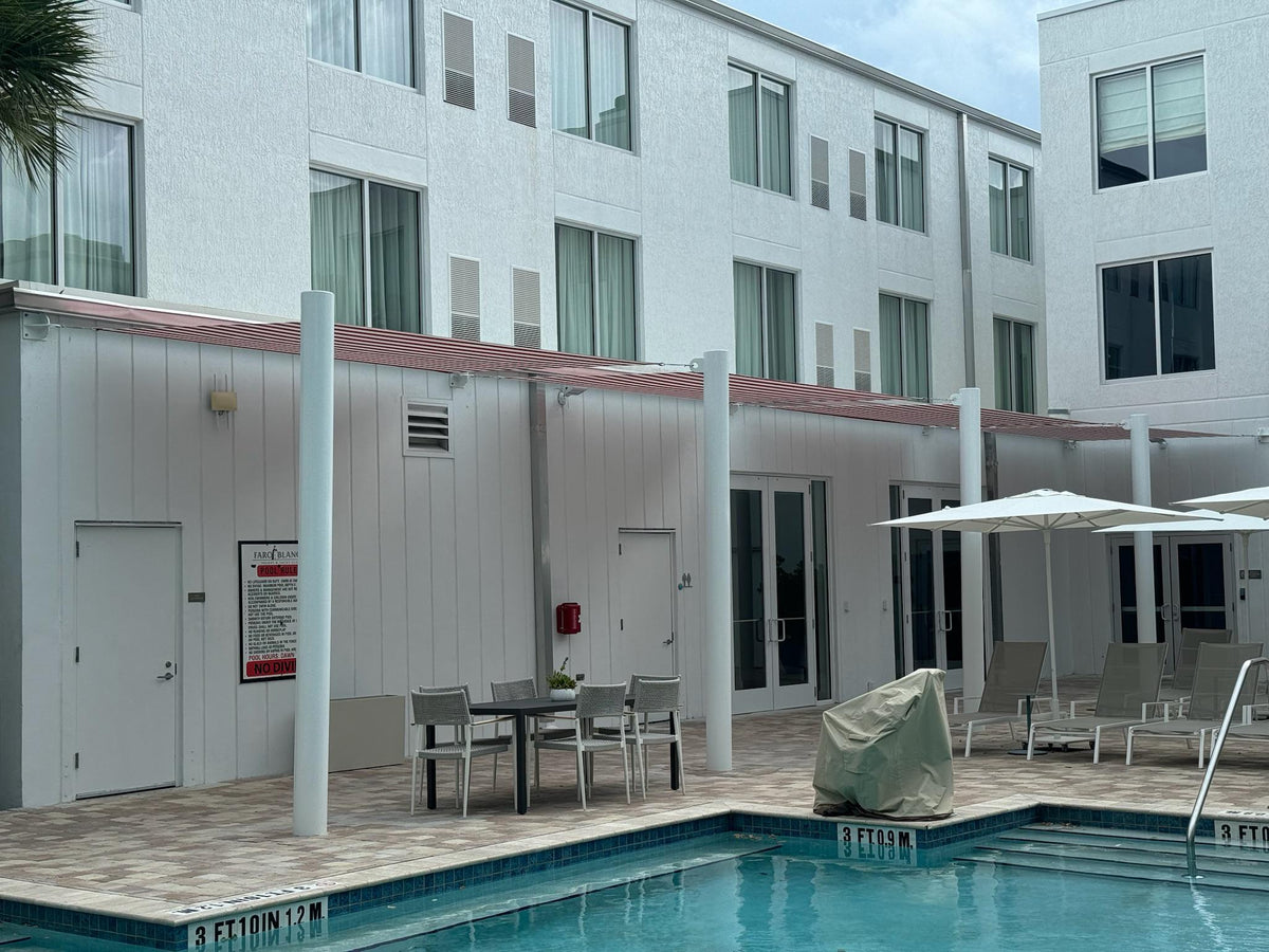 Metal structure with fixed red and white striped awnings over a pool walkway in Florida