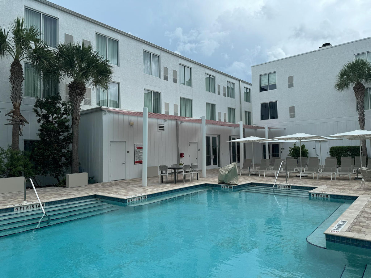 Freeform swimming pool with adjacent jacuzzi and brick paving in Miami